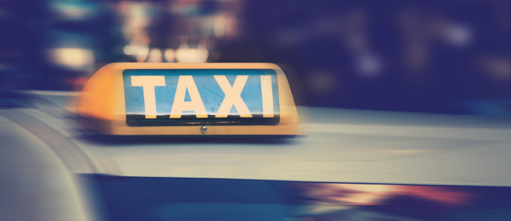 enseigne de taxi sur le toit d'un taxi la nuit. lumières de la ville dans le ciel